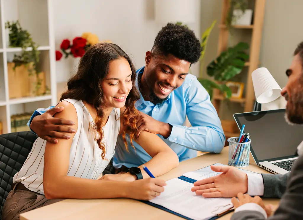 Young Latin American couple signing a contract with an agent in the office